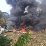 Destroços de avião militar C-130 Hércules que caiu na Colômbia com fumaça ao fundo