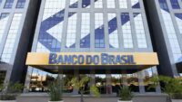 Fachada do Banco do Brasil com texto sobre calote de R$ 3,6 bilhões e inadimplência em alta