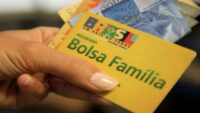 Cartao do Bolsa Familia em destaque diante de predio do Governo Federal
